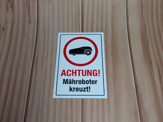 Lustiges Mähroboter kreuzt Schild