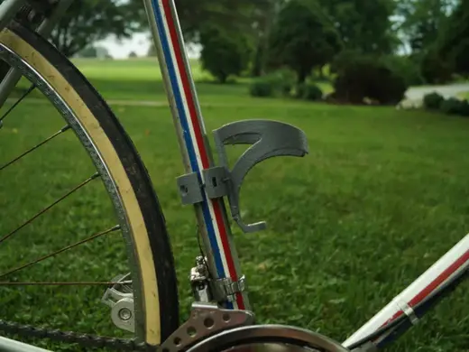 Water bottle cage with tube clamp