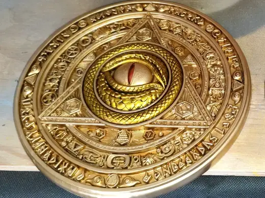 Medallón con estética iluminati con ojo de reptil